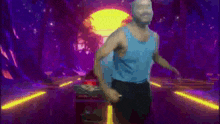 a man in a blue tank top is flexing his muscles in front of a microphone in a dark room .