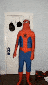 a person in a spiderman costume is standing in front of a door