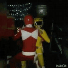 a red power ranger and a yellow power ranger are hugging each other .