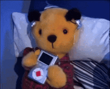 a teddy bear is wearing headphones and holding a small device
