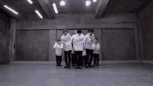 a group of young men are dancing in a room with a concrete wall