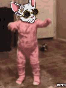a baby wearing pink pajamas and sunglasses with a cat face on it