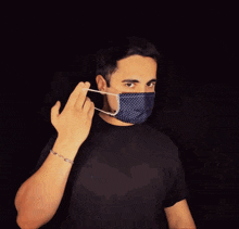 a man wearing a black shirt and a blue polka dot face mask