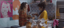 two women are standing in a kitchen with a sign on the wall that says ' a ' on it