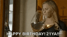 a woman is drinking a glass of wine and saying `` happy birthday ! 21 ya ! ''