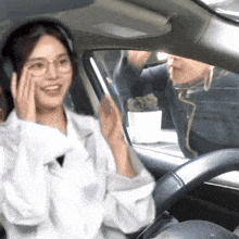 a woman wearing headphones is sitting in a car with a man behind her