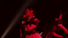 two girls in purple and white dresses singing into microphones
