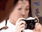 a woman taking a picture with a sign that says ' 아이유 ' in the background
