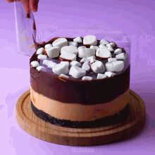 a cake with marshmallows on top of it is on a wooden cutting board