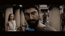 a man with a beard is looking at the camera with the word this in blue behind him