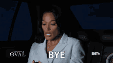 a woman sitting in a car with the word bye on her chest