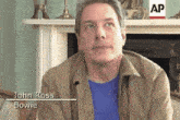 a man named john ross bowie is sitting in front of an ap fireplace