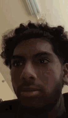 a close up of a man 's face with a beard and curly hair .