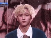 a young man with blonde hair is standing in front of a screen that says comeback xdinary heroes on it