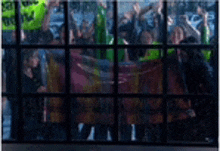 a group of people are standing in front of a window with a blurred image of a crowd .