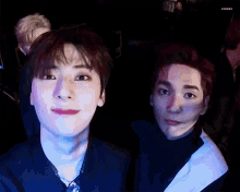 a group of young men are standing next to each other in a dark room and looking at the camera .