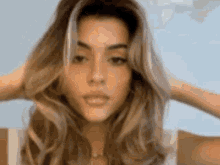 a close up of a woman 's face with her hair in her hands .