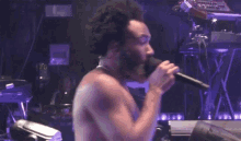 a shirtless man singing into a microphone in front of a keyboard