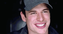 a close up of a man wearing a hat smiling .