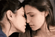 two women are kissing each other on the forehead in a close up of their faces .