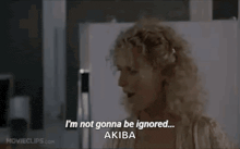 a woman is standing in front of a refrigerator and talking to a man .