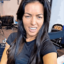 a woman with long black hair is smiling and looking at the camera while wearing a black shirt .