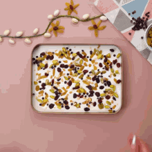 a tray filled with nuts and raisins on a pink surface