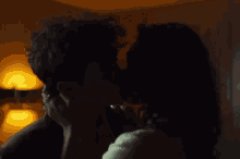 a man and a woman kissing in a dark room .