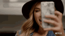 a woman is taking a selfie with her phone with a netflix logo in the corner