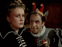 a man and a woman are standing next to each other and the woman is wearing a crown