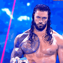 a shirtless wrestler with long hair and a tattoo on his chest is holding a championship belt .