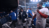 a man in a blue jays jacket talks to another man in a white jersey