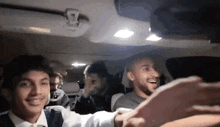 a group of men are taking a selfie in the back seat of a car .