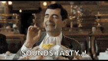 mr bean is eating a hamburger in a restaurant and saying `` sounds tasty ... '' .