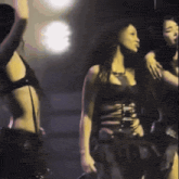 a group of women are dancing in a dark room and one of them is wearing a black top