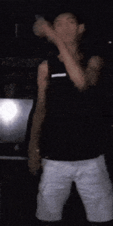a young man in a black tank top and white shorts is dancing