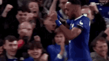 a soccer player is celebrating a goal with his teammates in front of a crowd .