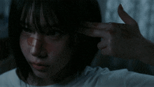 a close up of a person 's face with a hand pointing to their head