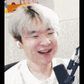 a man with white hair is smiling in front of a microphone while wearing headphones .