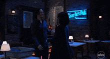a couple hugging in a dark room with abc written on the bottom right