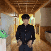 a young man in a school uniform stands in a hallway