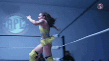 a woman in a yellow dress is in a wrestling ring with a logo that says opb