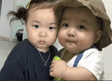 two babies are posing for a picture and one has a necklace on