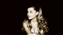 ariana grande is wearing a ponytail and a white top .