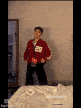 a young boy in a red jacket with the number 25 on it