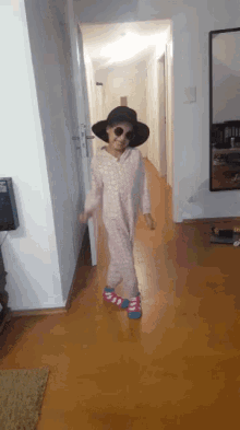 a little girl wearing a hat and sunglasses is dancing in a hallway