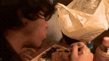 a person eating a piece of food with a plastic bag in the background with the letter d on the bottom