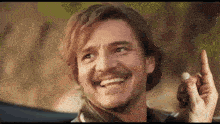 a man with a mustache is smiling and pointing up with his index finger .