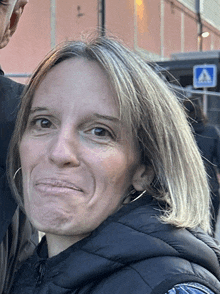 a woman making a funny face in front of a sign that says crosswalk