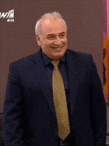 a man in a suit and tie smiles in front of a w7 hd sign
